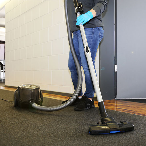 A cleaner vacuum cleaning an office floor